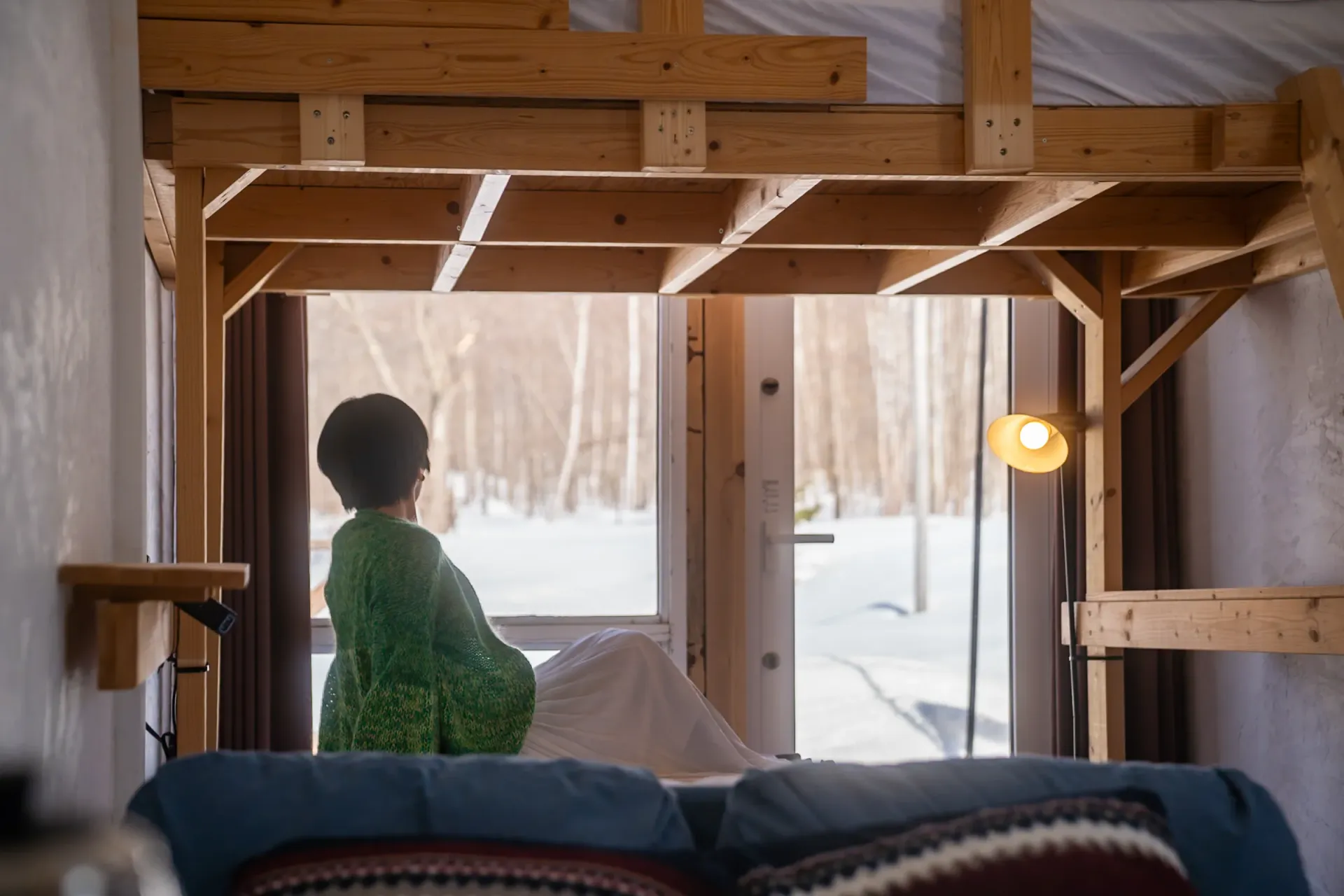 冬のキャンプ場の室内から外を眺める人