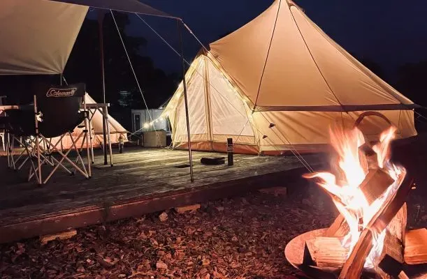 夜のキャンプサイトで焚き火とベルテント