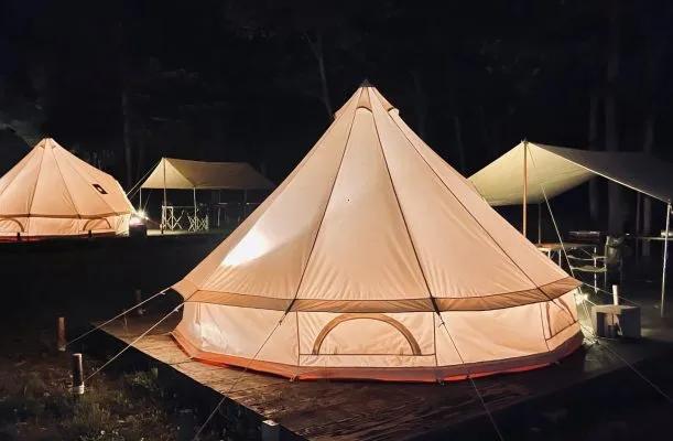 夜のキャンプ場に並ぶライトアップされたベルテント